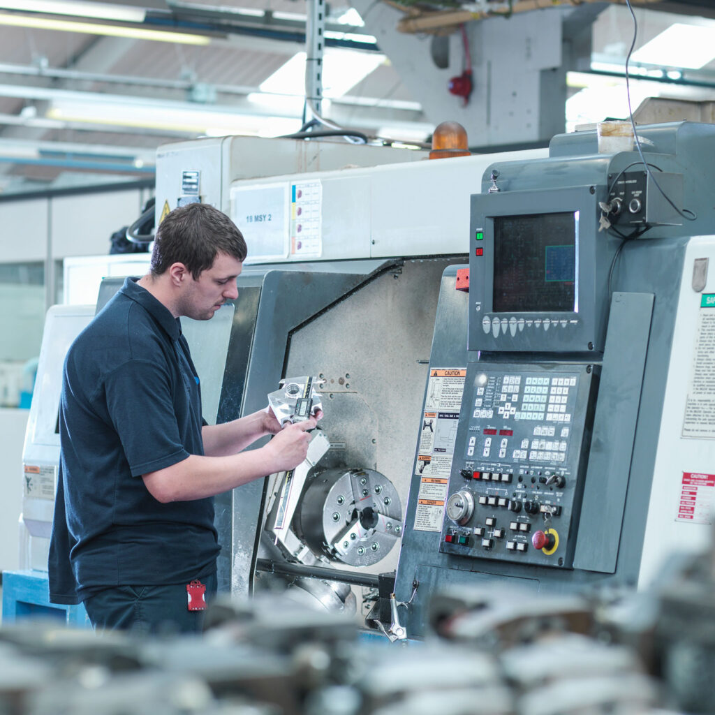 A CNC technician checks measurements